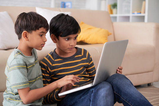 Indian kids sitting on floor and using laptop
