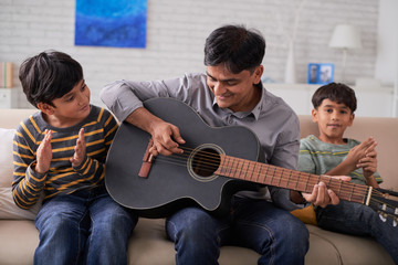 Father playing guitar and his sons singing