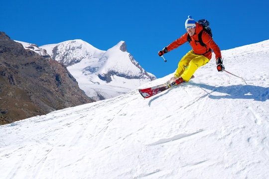 Skier skiing downhill in high mountains, Matterhorn area, Switzerland