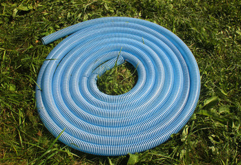 Blue and white corrugated plastic hose on green grass