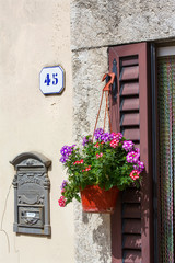 Fototapeta na wymiar Italian house exterior decorated with flowers in a pot