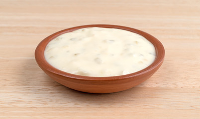 Small bowl of tartar sauce on a wood table.