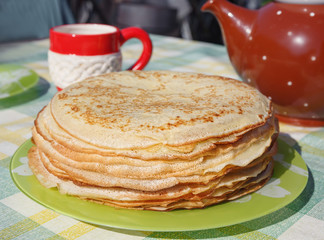 Pancakes , cup and teapot on a summer table .Focus concept.