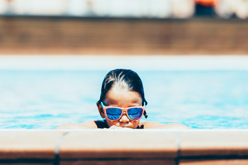 Boy in mirrored sunglasses relaxing in pool