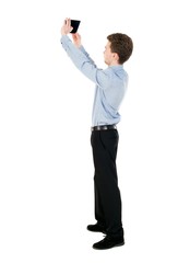 back view of standing business man photographing a phone or tablet. curly-haired businessman in light shirt pictures of the tablet that is in the sky.