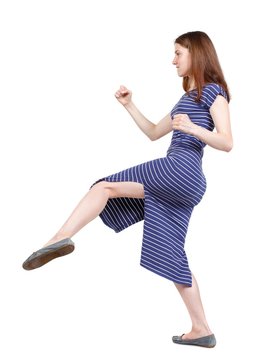 skinny woman funny fights waving his arms and legs. brunette in a blue striped dress in a fighting stance.