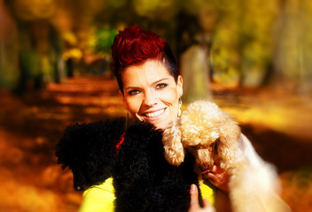 Cute girl with black and white dog smiling and hugging at the autumn park outdoors. Eye contact.