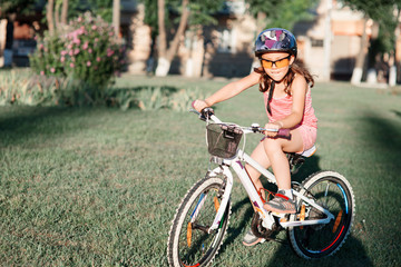 happy girl riding bicycle in summer sunset in the park