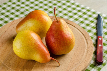 Ripe pear and a knife on wooden Board