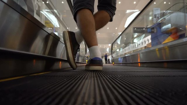 Back view of male legs on escalator at airport