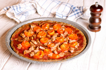 Pie with tomatoes and ham on a white table
