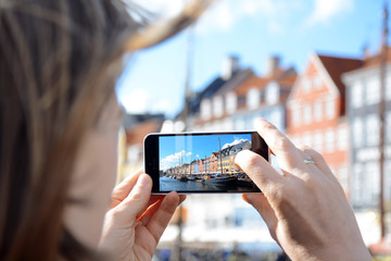 Frau fotografiert Hafen und Promenade Nyhavn in Kopenhagen, Dänemark mit Kamera von Smartphone