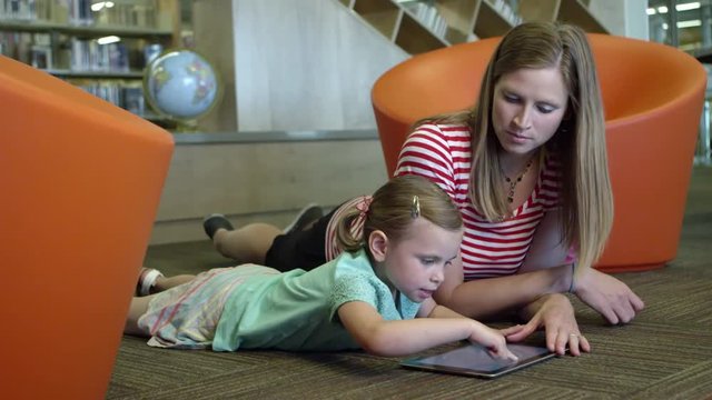 Mom and daughter in library using tablet