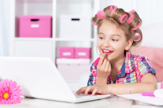little girl in hair curlers and laptop