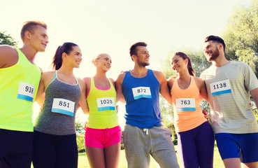 happy friends or couple with racing badge numbers