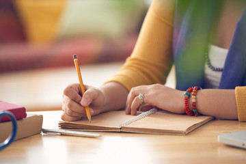 Hands of woman writing in her textbook