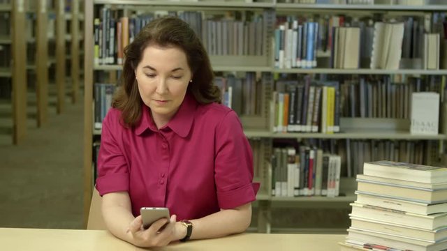 Woman using cellphone in library