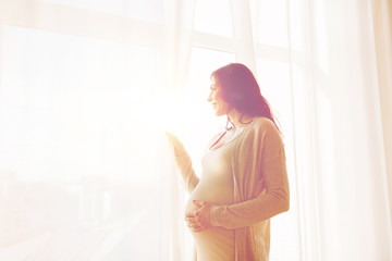 close up of happy pregnant woman looking to window