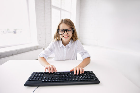 smiling girl in glasses with keyboard at school