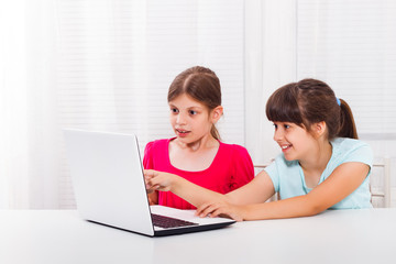 Little girls are using laptop and one little girl is surprised because of something she saw on it.
