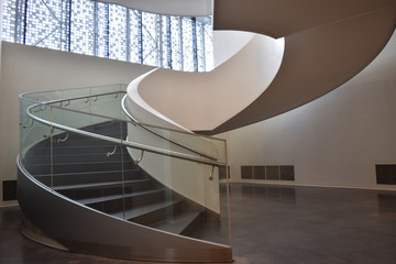 View of the entrance to the spiral staircase of a modern office building. Clear, measured proportions and soft, diffused light through the windows create a feeling of lightness and airiness.