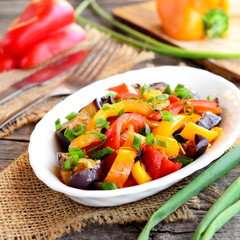 Vegetable stew on a plate. Vegetarian stew with braised eggplant, mixed peppers and green onions. Vegetable mix. Healthy food. Wooden background. Closeup