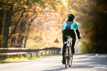 Fototapeta na wymiar Young sportsman riding bicycle outside in sunny autumn nature