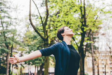 Half length of young beautiful brown hair woman outdoor in the city with arms wide open and eyes closed - relax, freedom, girl power concept