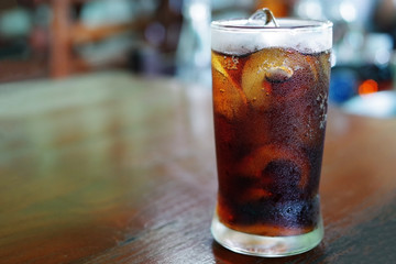 Iced cola with water drops condensed on glass surface, shallow d