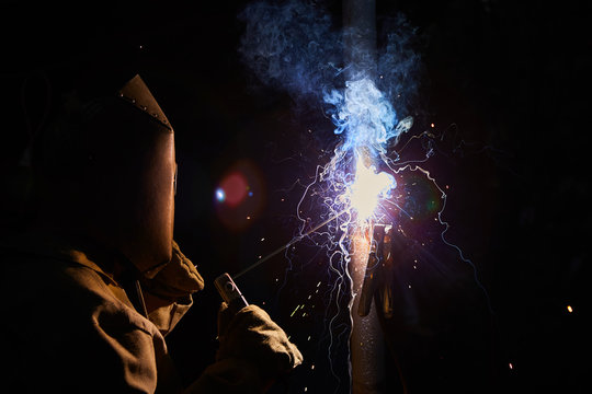 welder worker welding metal by electrode