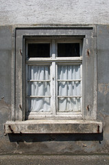 Fenster in verlassenem Altbau mit abgehängten Fensterläden