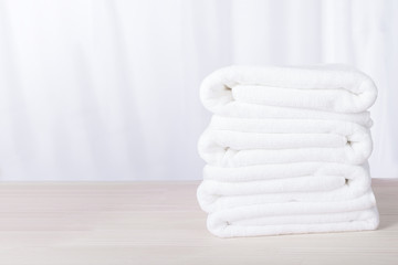 Stacked white plush spa hotel towels on table