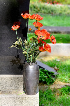 Kunstblumen in einer Vase am Grabstein
