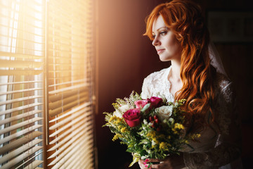 Beautiful red hair bride near window