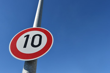 Verkehrsschild Tempo 10 kmh an Laterne vor blauem Himmel