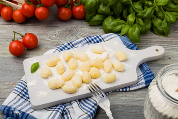 Uncooked homemade potato gnocchi with tomatoes or mushrooms with