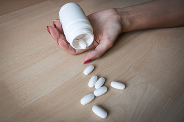 Fototapeta na wymiar Female hand with white bank, pills on a wooden background