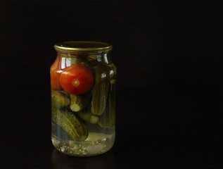 tasty and healthy food for your health
cucumbers and tomatoes in a glass jar.  dark background
