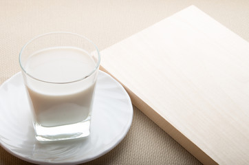 One glass of milk on a white saucer on tablecloth background