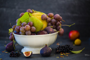 Beautiful still life with grapes and figs and other fruits on stone background.
