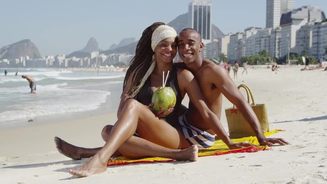 Portrait of Brazilian couple drinking coconut on beach