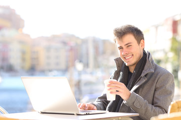 Man with laptop looking at camera in a bar