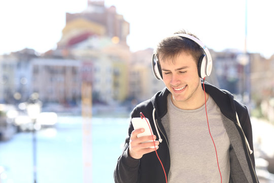 Teenager walking listening music from smart phone