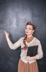 Thoughtful teacher in glasses with piece of chalk