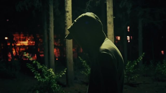Suspicious hooded figure walks in a dark park at night,100p