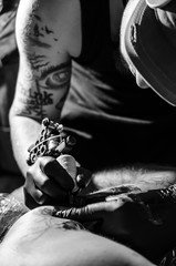 Tattoo artist with machine in his hand painting on human skin