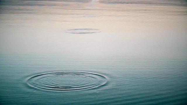 Stone skipping on water surface. Throwing a small flattened rock bouncing off water surface across body of water many times and finally sinking in the lake, river, sea or ocean