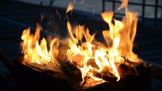 The firewood burning in a brazier closeup in the night.