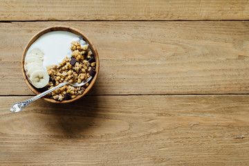 Homemade oatmeal chocolate granola with yogurt in wooden bowl