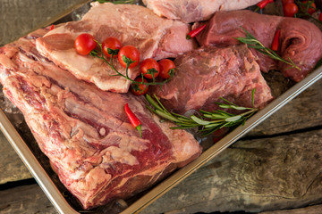 Tray with raw meat. Tomatoes and chili peppers. Veal and beef. Best source of protein.